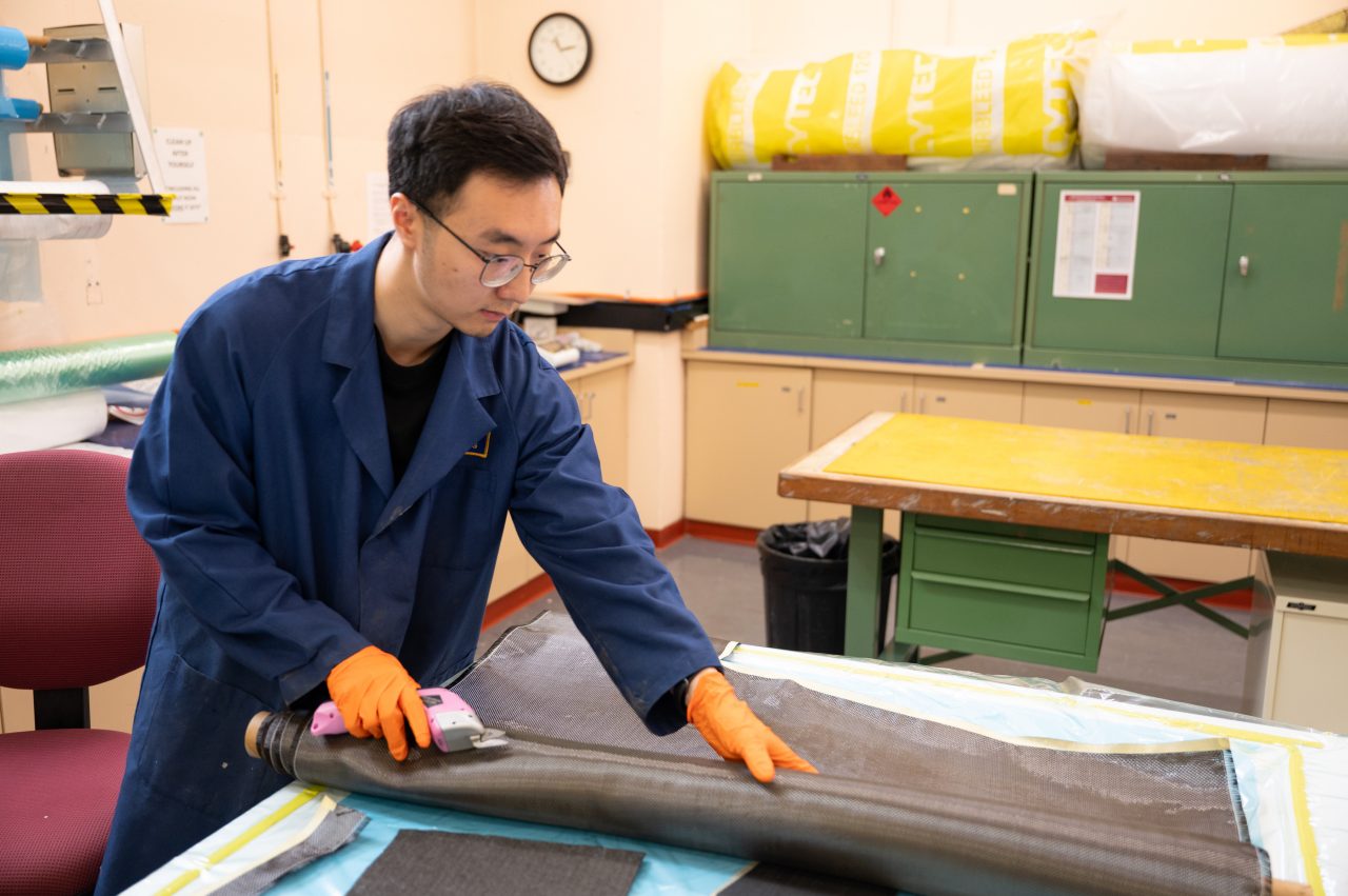 Dr Di He handles a sheet of carbon fibre.